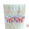 Boucles d'oreilles papillons colorés sur fleurs blanches avec pendentifs résine estampes et perles par Odacassie